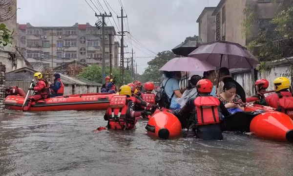 Nhân viên cứu hộ giúp sơ tán người dân bị mắc kẹt trên đường phố ngập lụt ở Bắc Hải (Quảng Tây, Trung Quốc). Ảnh: Reuters.