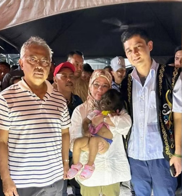 Vua Malaysia (trái) và Hoàng hậu (giữa) đang bế bé gái Missclyen Roland. Ảnh: ISTANA NEGARA. Vua Malaysia (trái) và Hoàng hậu (giữa) đang bế bé gái Missclyen Roland. Ảnh: ISTANA NEGARA.