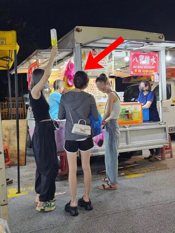 Cô gái (mặc áo khoác ghi) ra chợ đêm ăn vặt trong khi đang phải truyền dịch. Ảnh: TCNM.