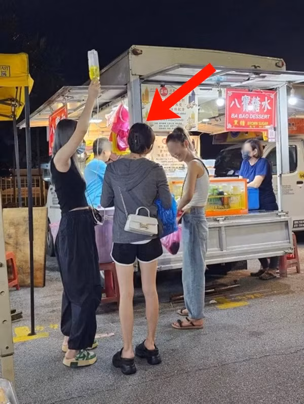 Cô gái (mặc áo khoác ghi) ra chợ đêm ăn vặt trong khi đang phải truyền dịch. Ảnh: TCNM.