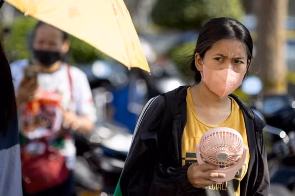 Một phụ nữ mang theo quạt ra phố ở Thái Lan. Ảnh: AFP.