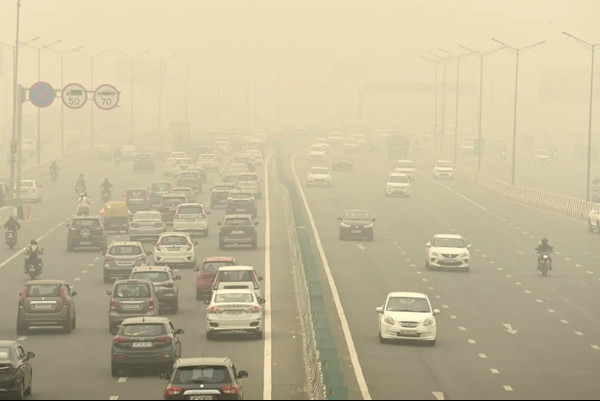 Xe cộ di chuyển trên con đường phủ sương mù và khói ở New Delhi. Ảnh: AP.