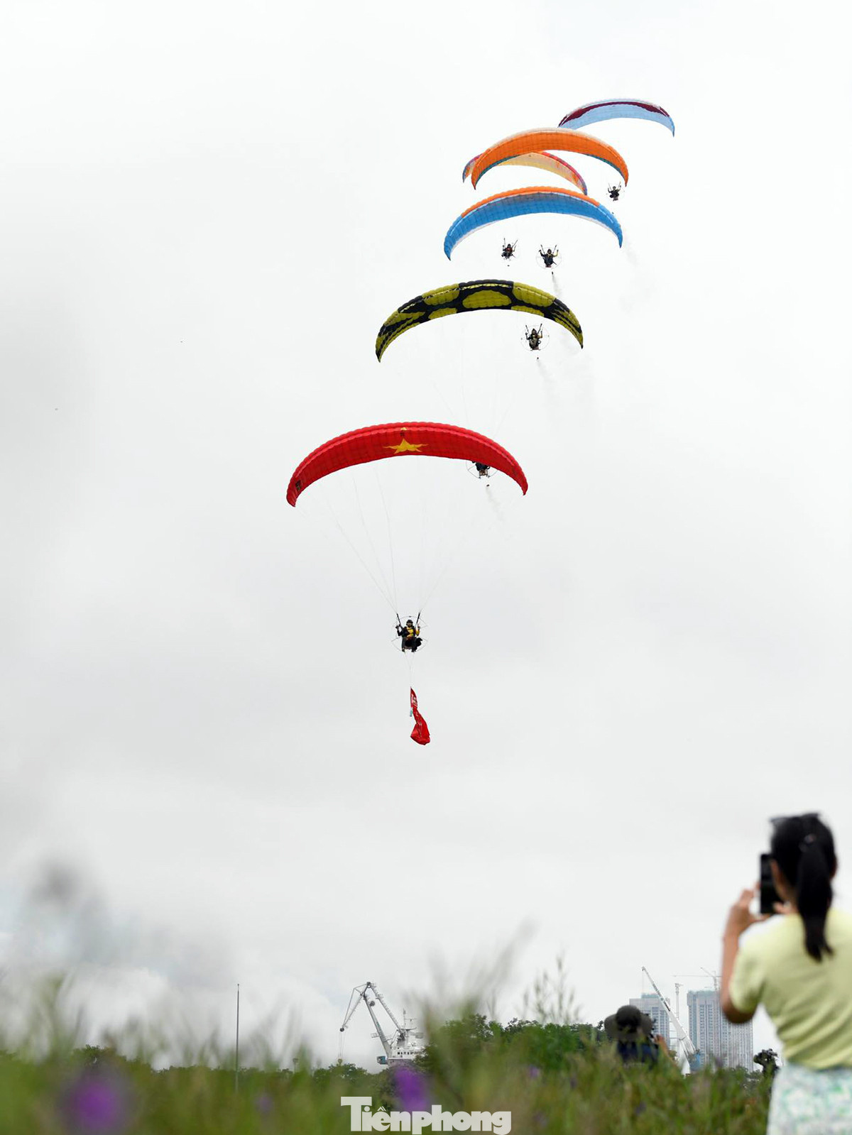 Các golfer và người theo dõi giải đấu bất ngờ với màn biểu diễn dù lượn có động cơ. Nhiều người chụp ảnh, ghi lại những hình ảnh ấn tượng này.