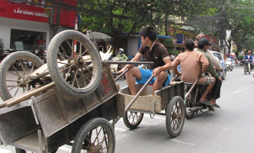 Bốn thanh niên trên một chiếc xe máy cà tàng, kéo theo một người nữa và ba chiếc xe thồ. Ảnh: Trường Phong..