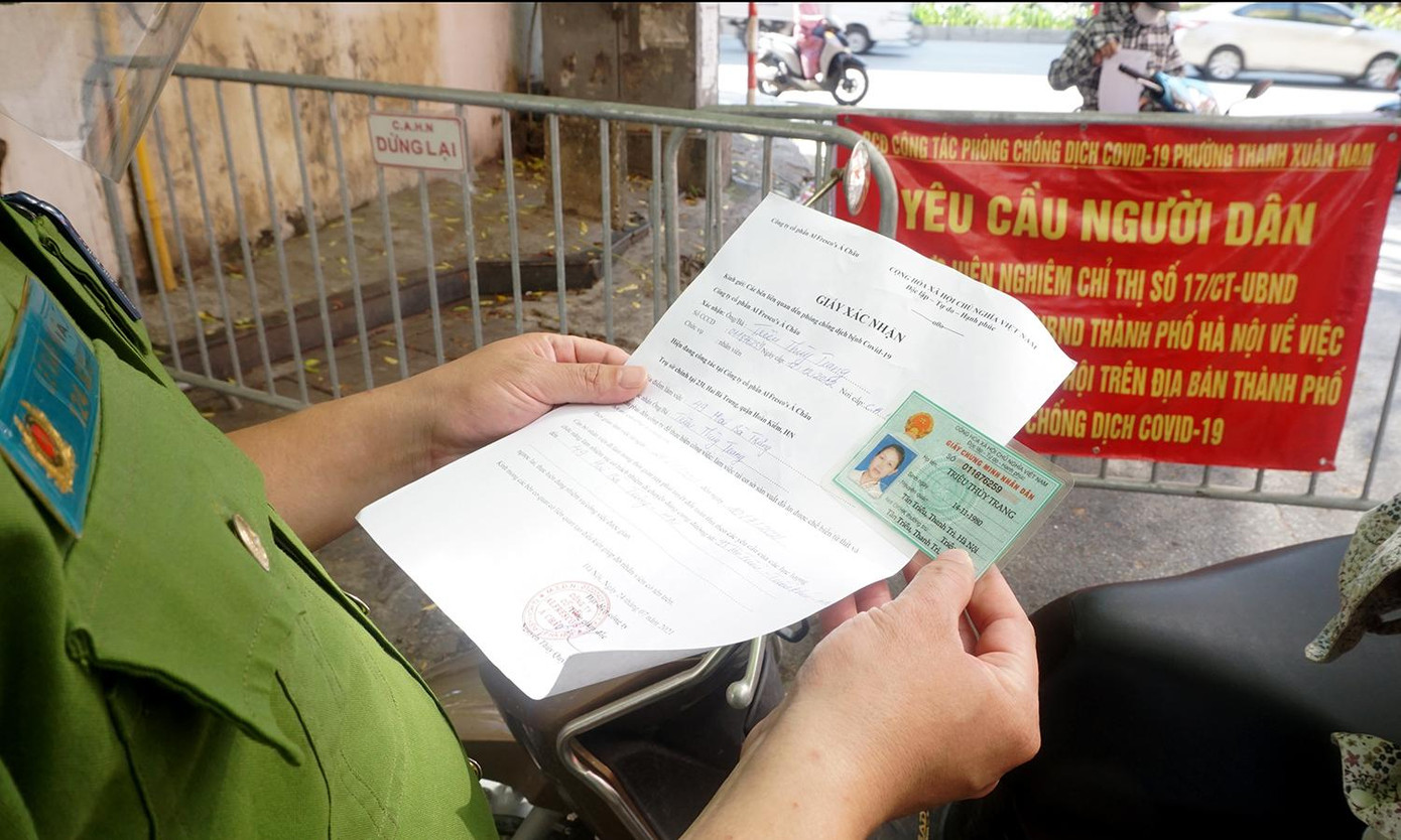 Cán bộ tại chốt đối chiếu giấy tờ tuỳ thân của người dân và giấy đi lại của công ty.