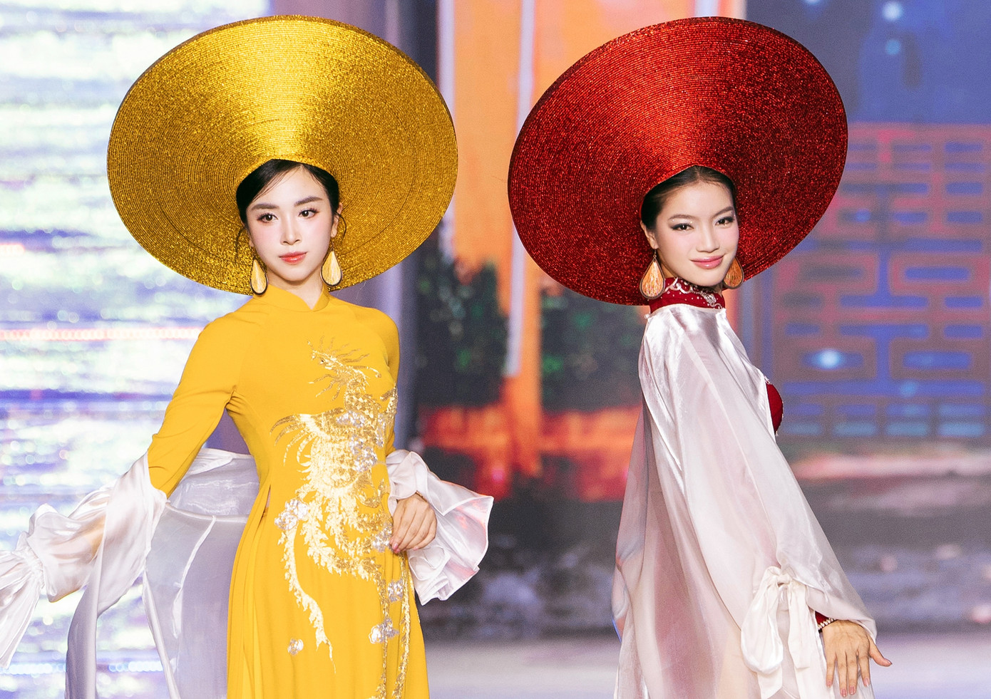 Á hậu Thuý An và Bích Tuyền mở màn cho BST với hai thiết kế tinh tế tỉ mỉ màu vàng và màu đỏ tím. Trang phục được lấy cảm hứng từ loài chim Phượng Hoàng cao quý, được xem là loài chim huyền thoại trong văn hóa phương Đông.