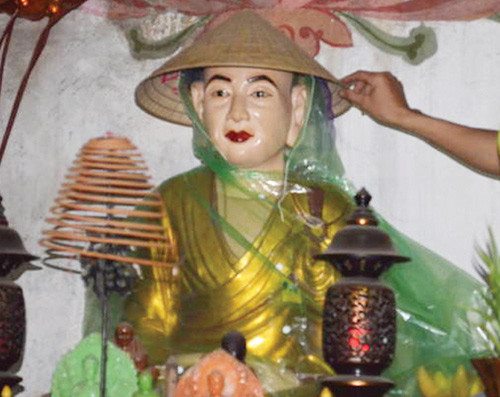 Tượng trong chùa Một Cột mặc áo mưa, đội nón chống dột - Ảnh: Hà Lê