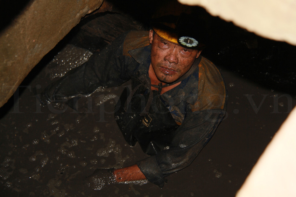 Đang làm việc, nước bùn bắn vào thành cống, đập vào mặt khiến mắt anh Hồ Thanh Sơn đỏ hoe. Ảnh: Trường Phong