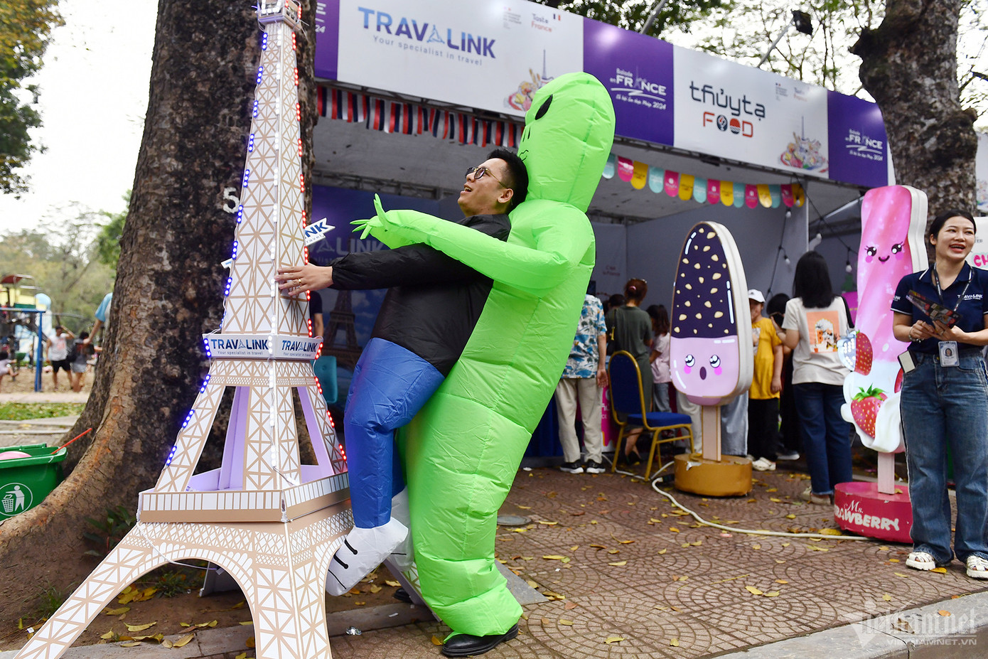 Mô hình tháp Eiffel được đặt trước một gian hàng công ty du lịch. Anh Huy (trong ảnh) đang làm một trò chơi hài hước nhằm gây sự chú ý cho người qua lại. Dụng cụ anh mặc vào người được mua từ nước ngoài về, chưa từng xuất hiện ở sự kiện lớn nào tại Việt Nam.
