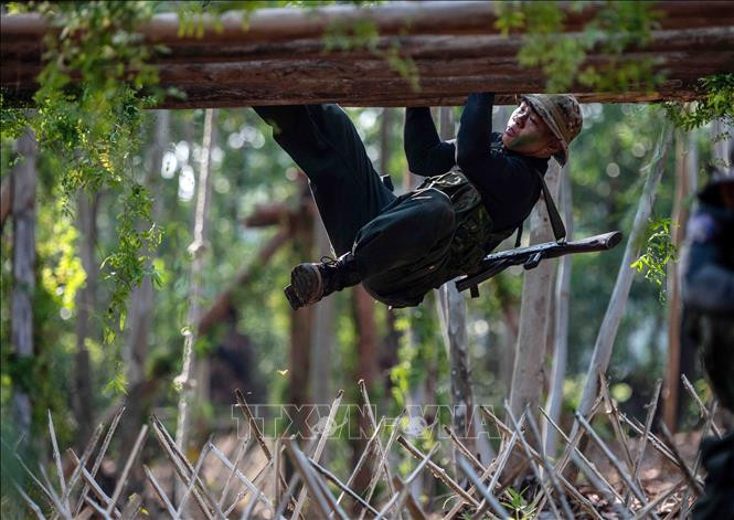 Chiến sĩ CSCĐ chống khủng bố thực hiện bài tập đu người trên các thanh gỗ để vượt qua hàng trăm cọc tre vót nhọn đầu ở phía dưới.