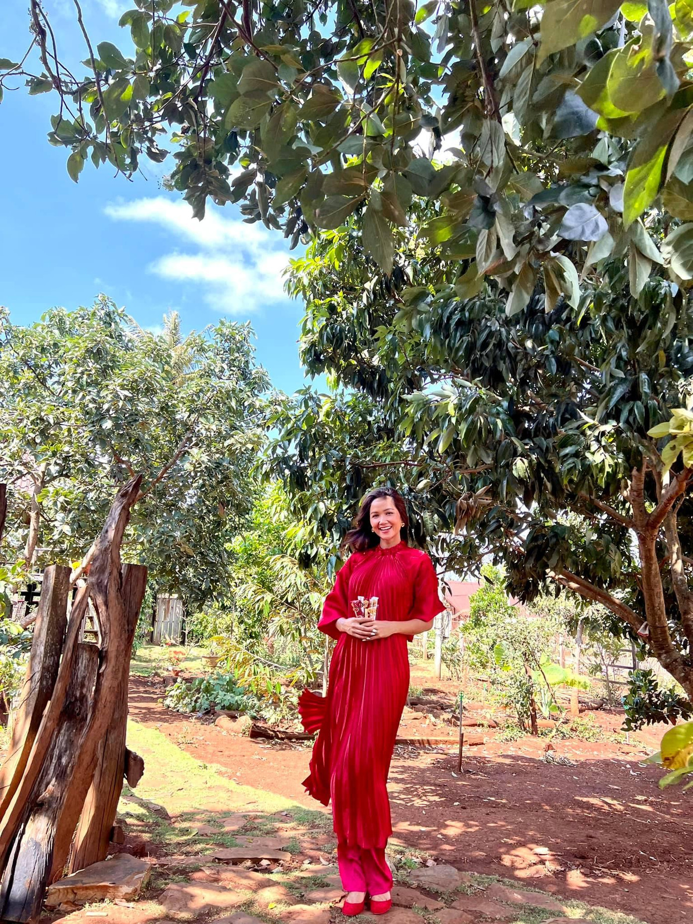 Không hẹn mà gặp, Hoa hậu H'Hen Niê cũng chọn áo dài tông màu đỏ dáng xếp ly khi đi chúc Tết ngày mùng 1.