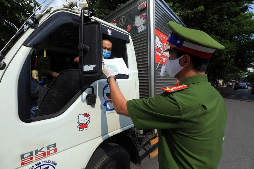 Công an kiểm tra giấy đi đường và giấy phép vận chuyển hàng hóa thiết yếu của các phương tiện vận tải. (Ảnh: Tuấn Anh/TTXVN)