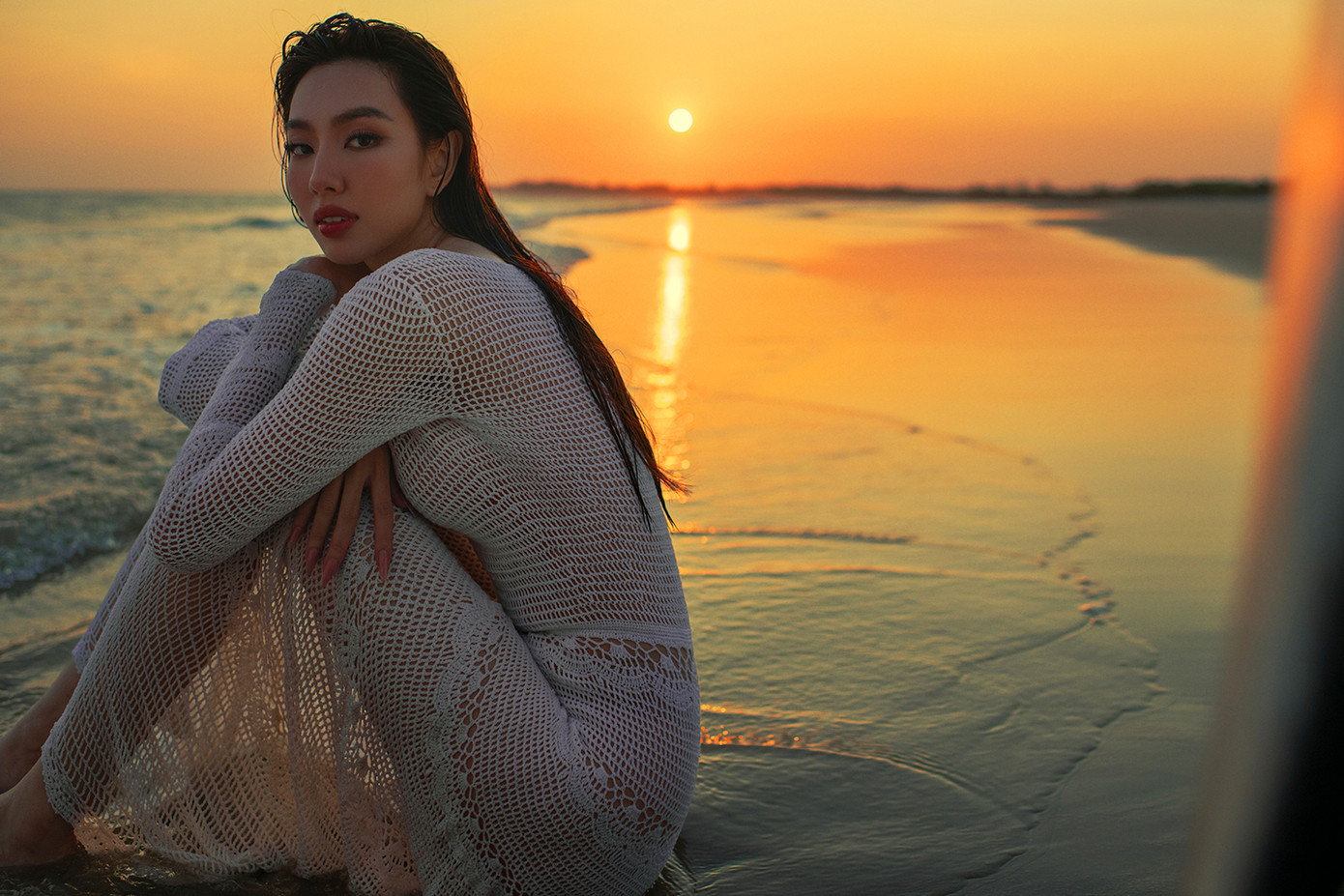 Người đẹp và ê-kíp cũng chịu khó lăn lộn trên biển cả ngày trời để canh khoảnh khắc hoàng hôn buông xuống. Diện bộ váy trắng chất liệu lưới xuyên thấu, Thùy Tiên khoe khéo thân hình quyến rũ dưới ánh chiều tà.