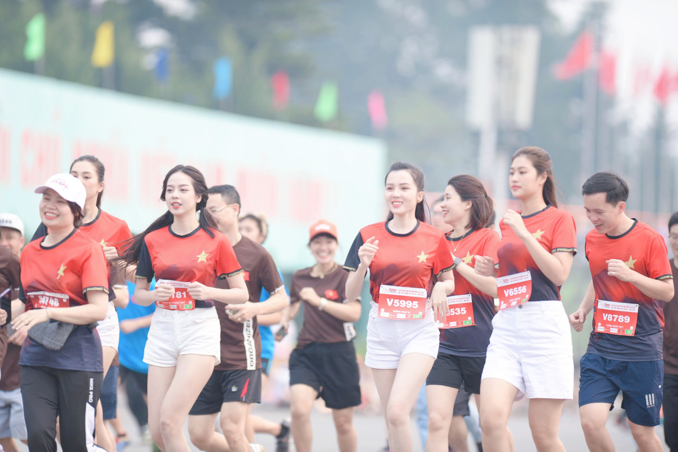 Dàn người đẹp mặc áo chạy đồng phục của giải đấu, rạng rỡ trên đường chạy.