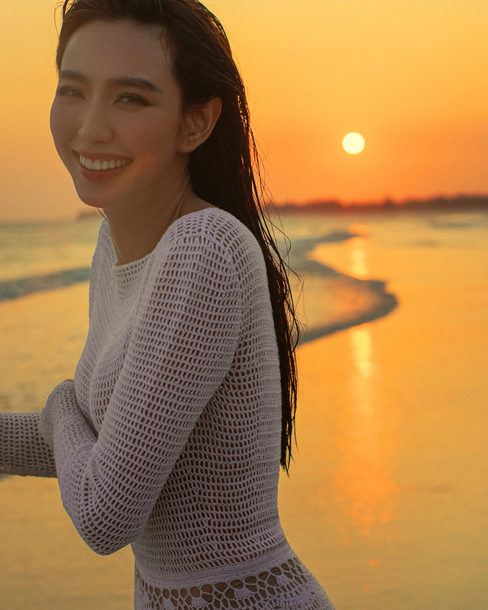 Người đẹp và ê-kíp cũng chịu khó lăn lộn trên biển cả ngày trời để canh khoảnh khắc hoàng hôn buông xuống. Diện bộ váy trắng chất liệu lưới xuyên thấu, Thùy Tiên khoe khéo thân hình quyến rũ dưới ánh chiều tà.