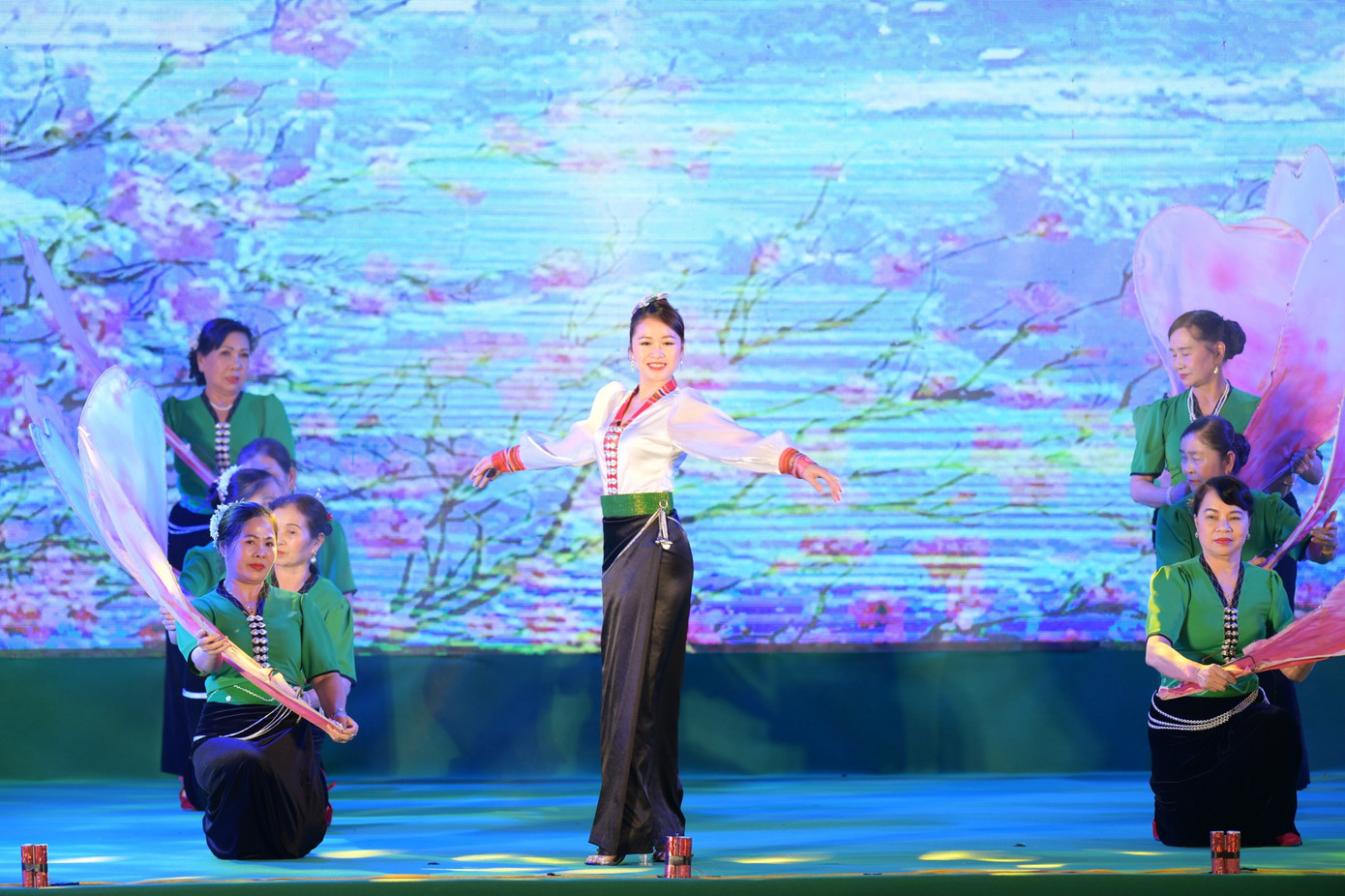 Mở đầu chương trình là màn trình diễn trang phục dân tộc của 11 dân tộc: Thái, Giáy, Lào, Mảng, Hà Nhì, La Hủ, Cống, Si La, Dao, Mông, Lự. Cô gái Thái xuất hiện với áo cóm và váy ống đứng màu đen của ngành Thái trắng. Chiếc áo cóm bó sát thân, trước ngực, hàng cúc bạc hình con bướm nối dài từ cổ áo hình chữ V đến bụng tạo nên điểm nhấn. Tà váy đen ống đứng được cố định bằng chiếc thắt lưng dài thêu hoa văn hai đầu.