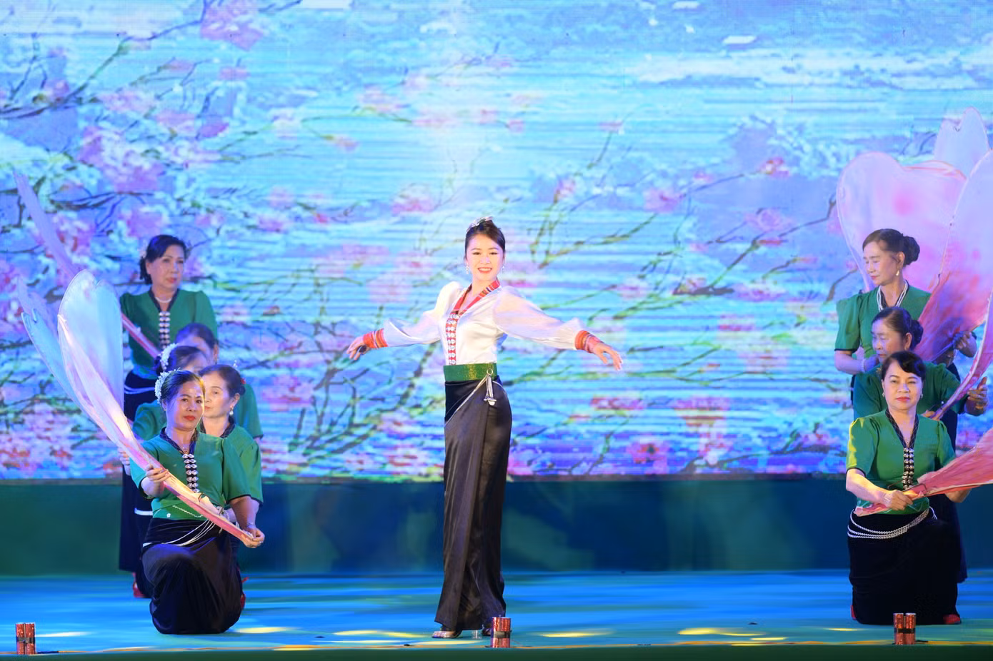 Mở đầu chương trình là màn trình diễn trang phục dân tộc của 11 dân tộc: Thái, Giáy, Lào, Mảng, Hà Nhì, La Hủ, Cống, Si La, Dao, Mông, Lự. Cô gái Thái xuất hiện với áo cóm và váy ống đứng màu đen của ngành Thái trắng. Chiếc áo cóm bó sát thân, trước ngực, hàng cúc bạc hình con bướm nối dài từ cổ áo hình chữ V đến bụng tạo nên điểm nhấn. Tà váy đen ống đứng được cố định bằng chiếc thắt lưng dài thêu hoa văn hai đầu. Mở đầu chương trình là màn trình diễn trang phục dân tộc của 11 dân tộc: Thái, Giáy, Lào, Mảng, Hà Nhì, La Hủ, Cống, Si La, Dao, Mông, Lự. Cô gái Thái xuất hiện với áo cóm và váy ống đứng màu đen của ngành Thái trắng. Chiếc áo cóm bó sát thân, trước ngực, hàng cúc bạc hình con bướm nối dài từ cổ áo hình chữ V đến bụng tạo nên điểm nhấn. Tà váy đen ống đứng được cố định bằng chiếc thắt lưng dài thêu hoa văn hai đầu.