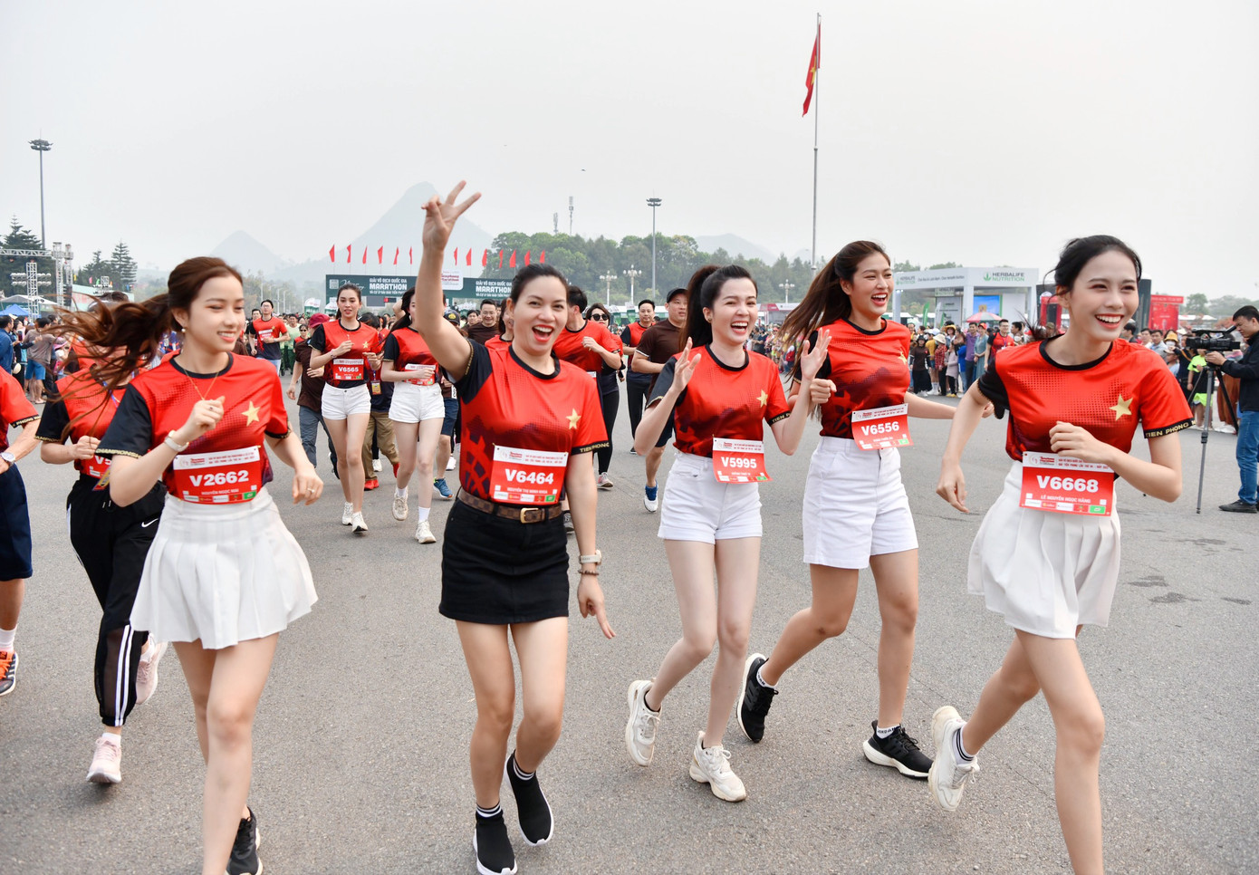 Dàn người đẹp mặc áo chạy đồng phục của giải đấu, rạng rỡ trên đường chạy.