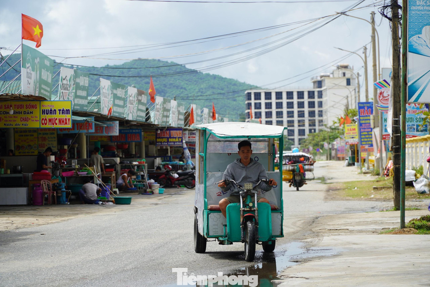 Đường giao thông bị thu hẹp, xe chở khách dịch vụ đi trước những ki ốt nằm trên hành lang đê biển.