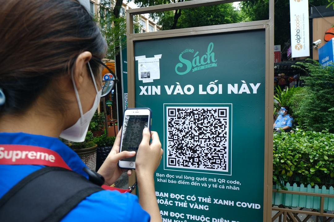 Người dân thực hiện khai báo thẻ vắc xin COVID-19, khai báo y tế, rửa tay sát khuẩn trước khi vào đường sách.