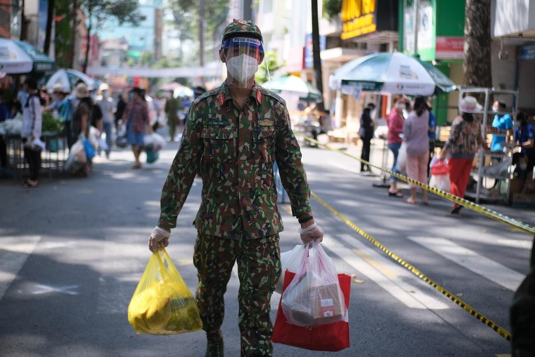 Ngay từ sáng sớm các ngày, những chiến sĩ thuộc sư đoàn 330, quân khu 4 có mặt tại chợ “lưu động” trên đường Trần Bình Trọng, phường 3, quận 5, TP.HCM hướng dẫn người dân giữ khoảng cách khi vào chợ và xách đồ giúp dân.