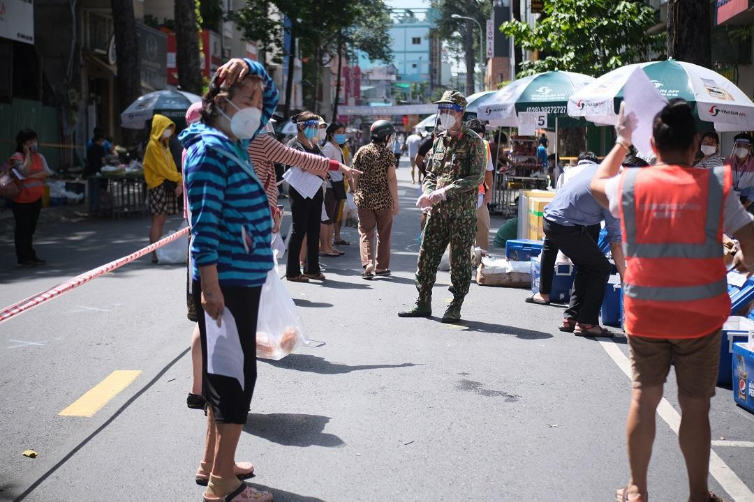 Bộ đội hướng dẫn người dân đảm bảo khoảng cách khi mua hàng.