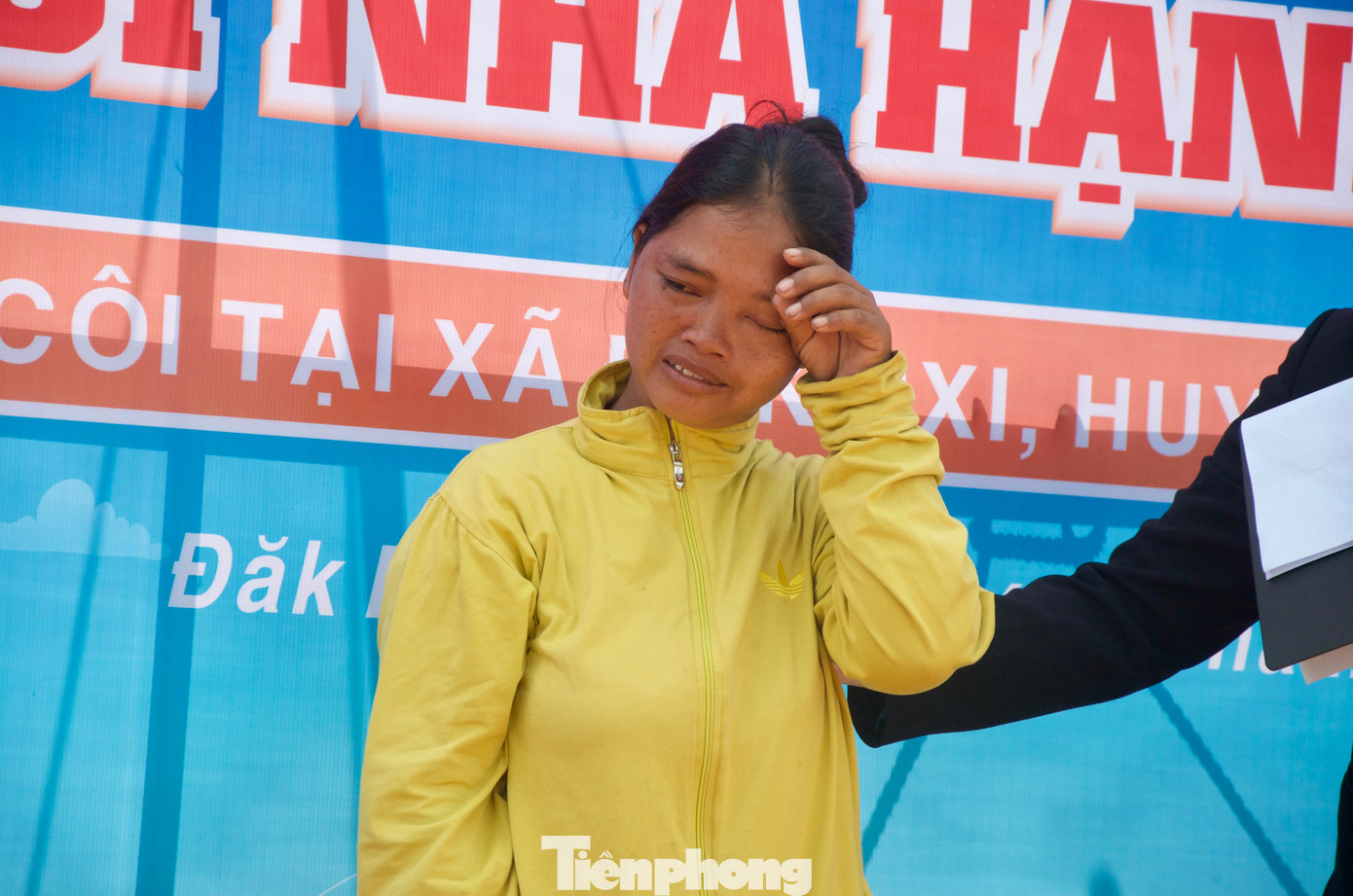 Gia đình anh A Chính có 10 người, trong đó anh nhận nuôi 5 cháu mồ côi cả bố lẫn mẹ. Con đầu Y Bích hiện đang học tại trường TH-THCS xã Đăk Pxi, các em còn nhỏ ở nhà với bố. Nhà đông con, hằng ngày anh A Chính phải đi làm rất nhiều công việc từ nương rẫy, phụ hồ,... Trong ảnh: Vợ anh A Chính xúc động cảm ơn nguồn tài trợ từ T.Ư Đoàn.