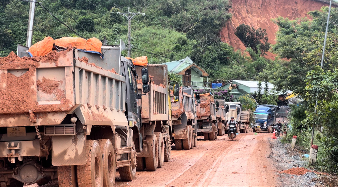 Hàng chục xe tải chờ để vận chuyển đất sạt lở.