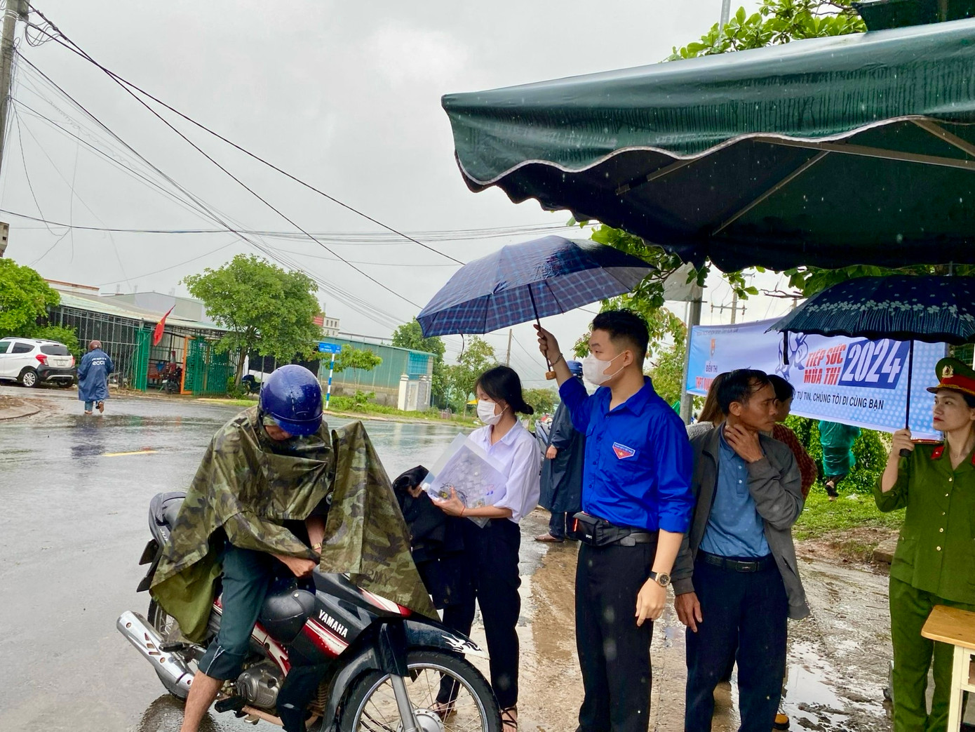 Sáng 27/6, huyện Sa Thầy (Kon Tum) bất chợt đổ cơn mưa rào, các thí sinh tại điểm thi này phải đội mưa vào thi.