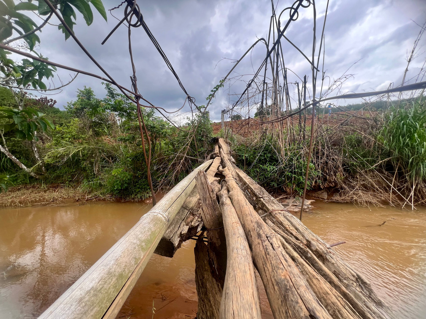 Các trụ cầu bằng gỗ bị mục nát, hai bên thành cầu là các sợi dây sắt bị gỉ