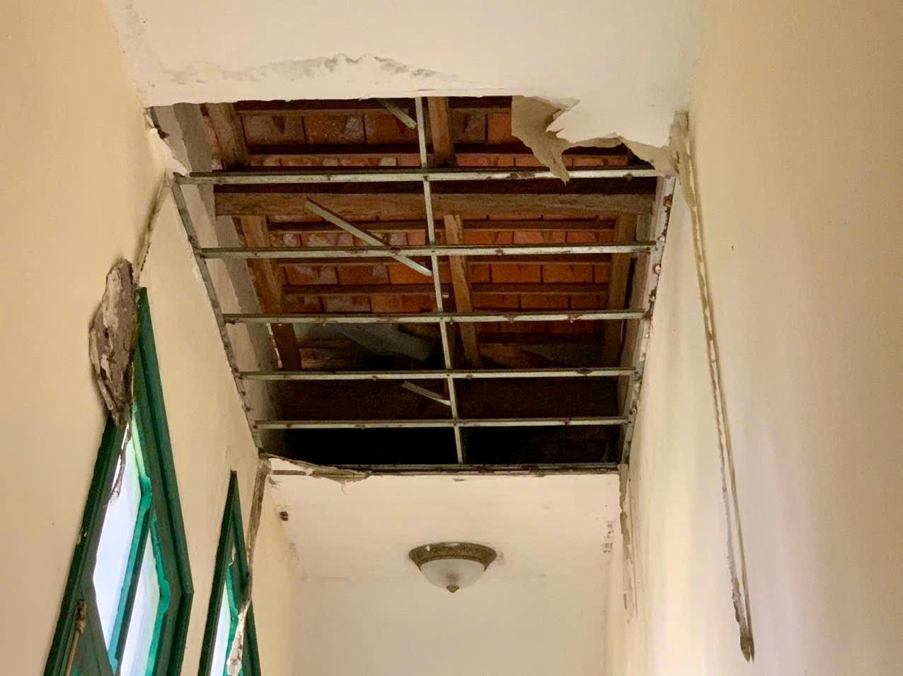 Thạch cao trần nhà rớt xuống từng mảng để lộ cả ngói lợp mái nhà.