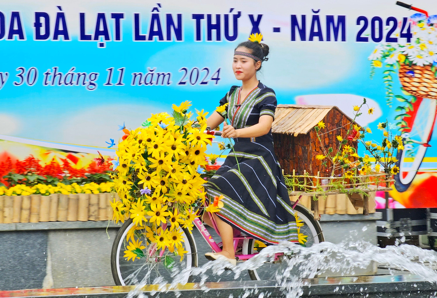 Mô hình nhà sàn, hoa dã quỳ được nữ giáo viên diện trang phục người dân tộc trường Mầm non Tà Nung trình diễn.