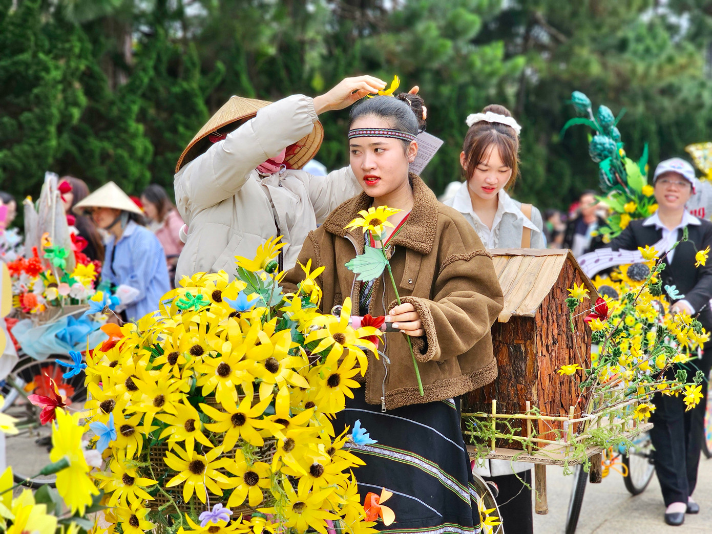 Mô hình nhà sàn, hoa dã quỳ được nữ giáo viên diện trang phục người dân tộc trường Mầm non Tà Nung trình diễn.