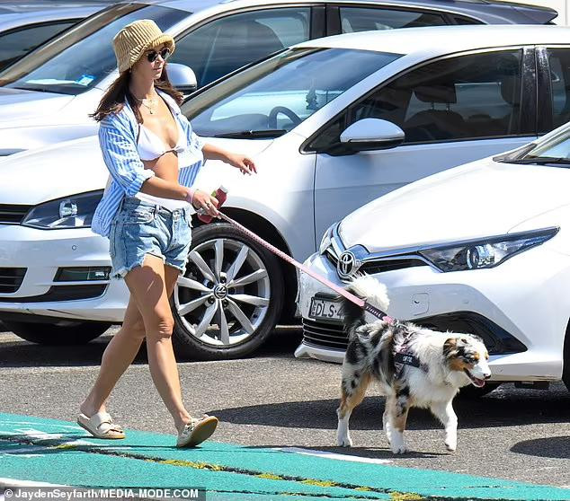 Sau khi thư giãn ở biển, Brittany Hockley dắt chó đi dạo vẫn với áo tắm, thêm áo sơ mi và quần short jean cá tính.