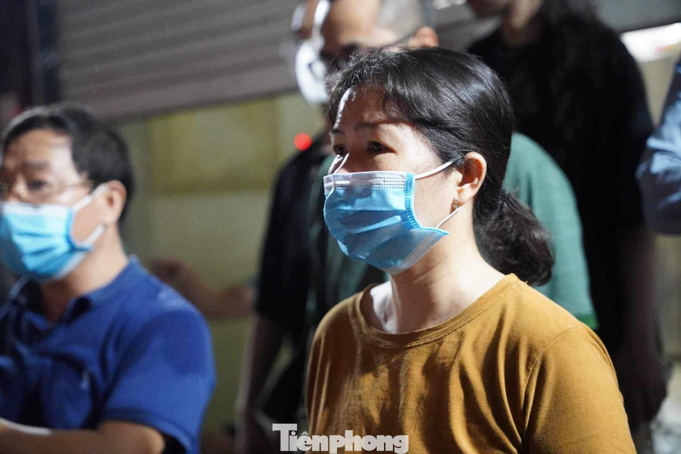 Mẹ của một người sống trong chung cư đứng chờ tin con, an tâm khi biết con an toàn.