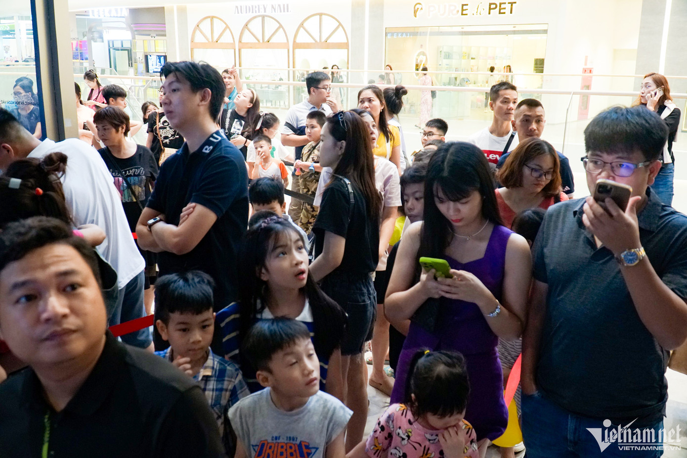 Nhiều phụ huynh và trẻ nhỏ đứng xếp hàng tại khu vực vui chơi dành cho trẻ nhỏ trong trung tâm thương mại.