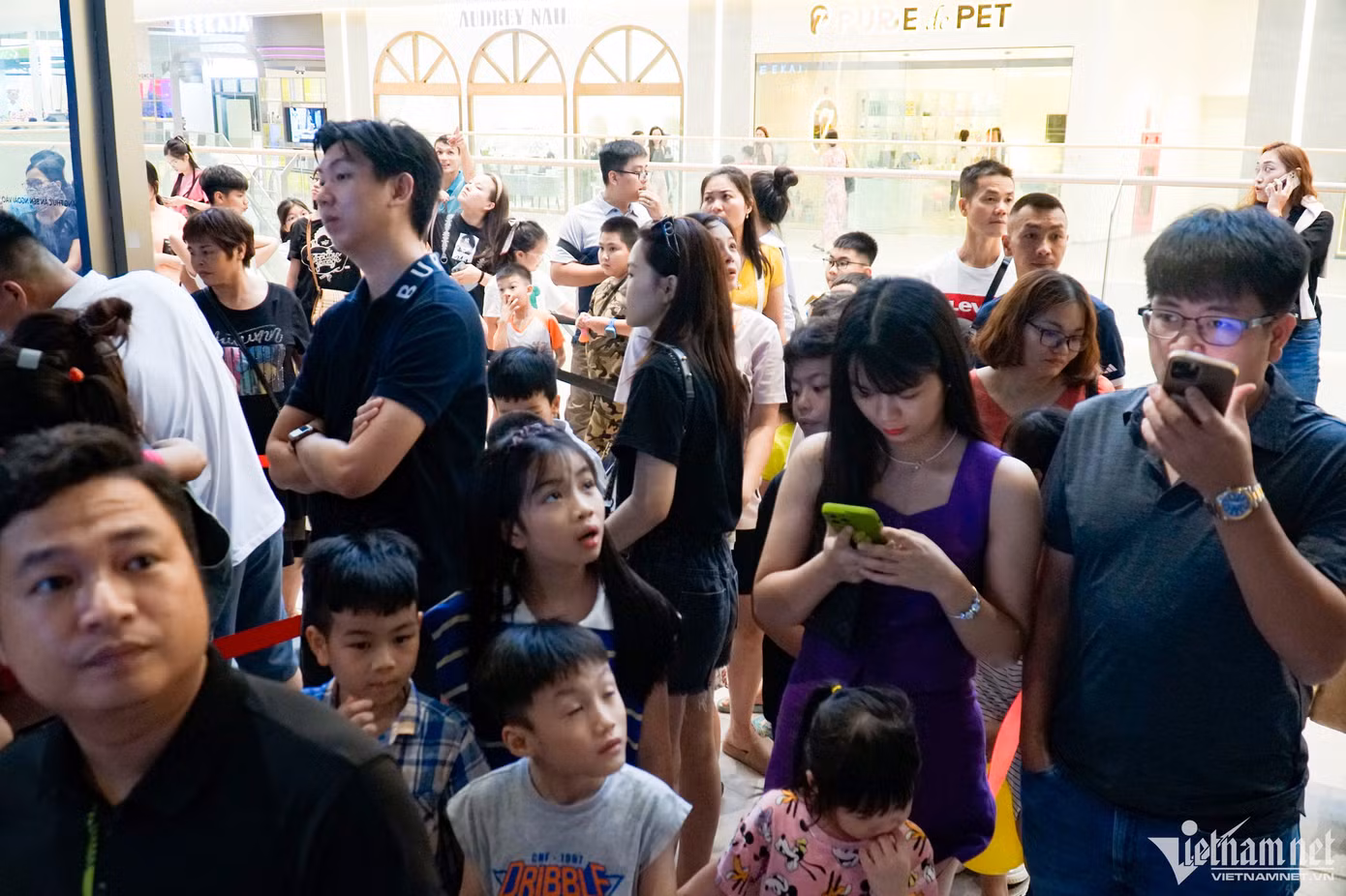 Nhiều phụ huynh và trẻ nhỏ đứng xếp hàng tại khu vực vui chơi dành cho trẻ nhỏ trong trung tâm thương mại.