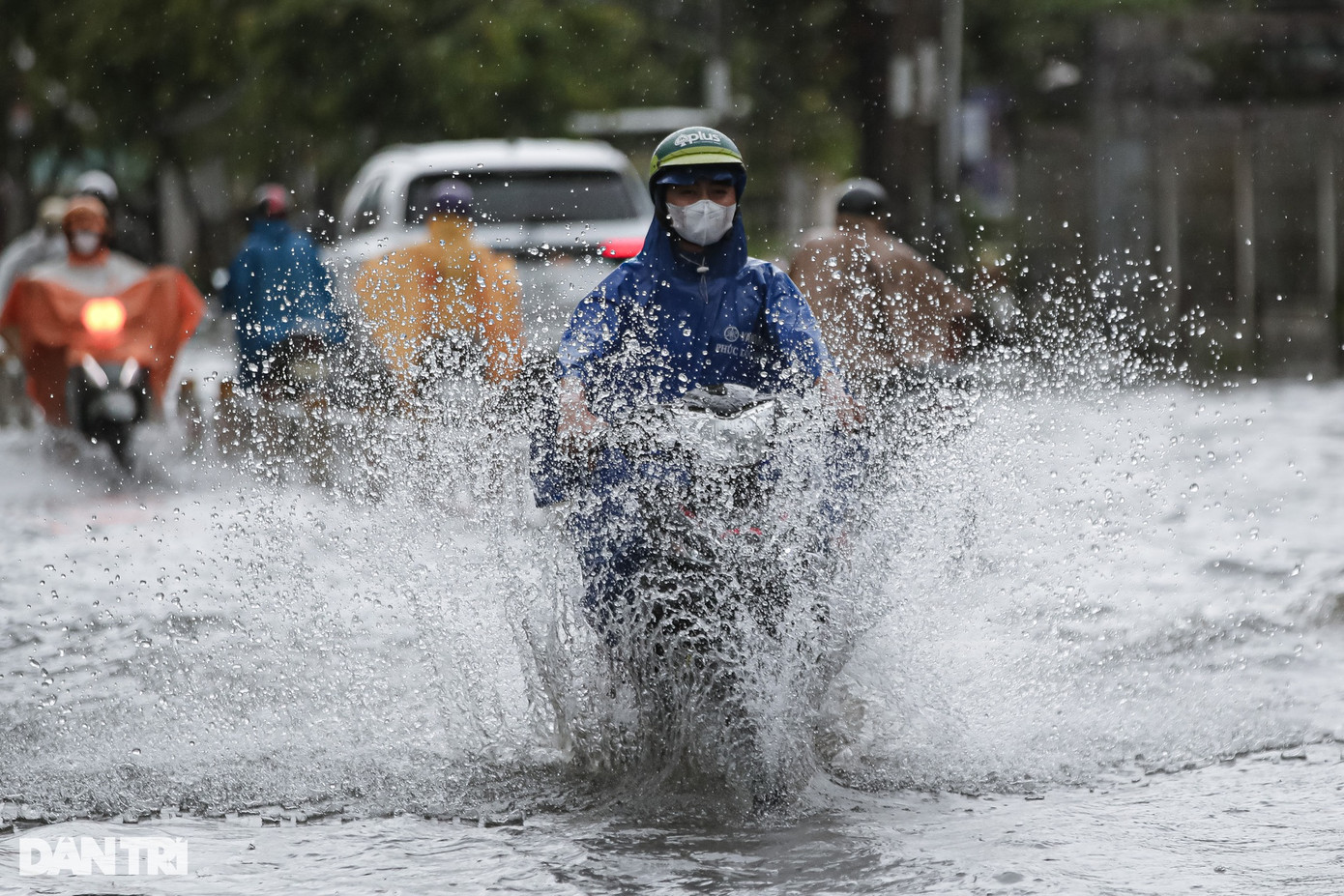 Một người đàn ông di chuyển qua đoạn ngập với tốc độ cao khiến nước bắn tung tóe.