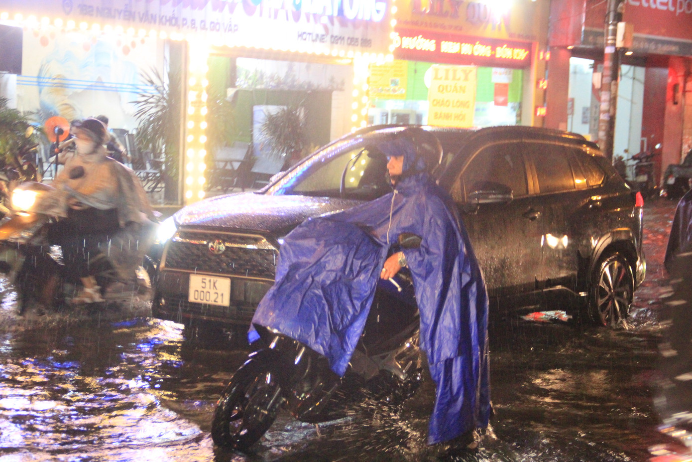 Mưa lớn, nước ngập, người dân chật vật di chuyển trên đường.