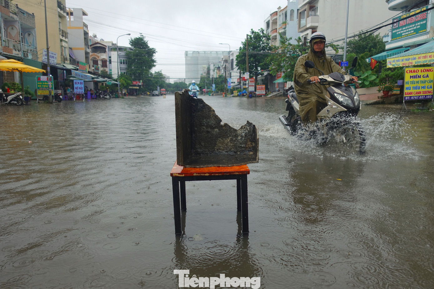 Nước ngập sâu trên đường người dân phải đặt ghế trước vị trí “ổ gà” nhằm cảnh báo người đi đường. Ảnh: Hữu Huy