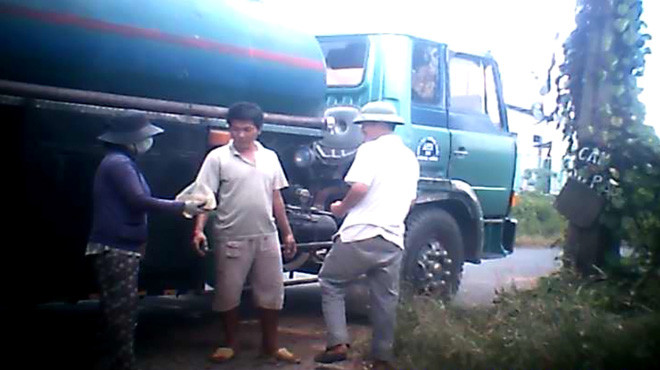 Tài xế xe bồn nhận tiền bán dầu tại một điểm tập kết trên quốc lộ 1A, đoạn qua thị xã Dĩ An, Bình Dương - Ảnh: Tuổi Trẻ