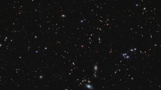 Kính thiên văn James Webb phát hiện ra một quasar được cung cấp năng lượng từ hố đen (chấm nhọn màu hồng ở giữa hình ảnh) có niên đại từ một tỷ năm đầu tiên sau Vụ nổ lớn. (Ảnh: NASA, ESA, CSA, S. Lilly (ETH Zurich), D. Kashino (Đại học Nagoya), J. Matthee (ETH Zurich), C. Eilers (MIT), R. Simcoe (MIT), R. Bordoloi (MIT), R. Mackenzie (ETH Zurich), A. Pagan (STScI))