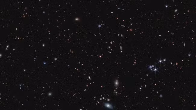 Kính thiên văn James Webb phát hiện ra một quasar được cung cấp năng lượng từ hố đen (chấm nhọn màu hồng ở giữa hình ảnh) có niên đại từ một tỷ năm đầu tiên sau Vụ nổ lớn. (Ảnh: NASA, ESA, CSA, S. Lilly (ETH Zurich), D. Kashino (Đại học Nagoya), J. Matthee (ETH Zurich), C. Eilers (MIT), R. Simcoe (MIT), R. Bordoloi (MIT), R. Mackenzie (ETH Zurich), A. Pagan (STScI))