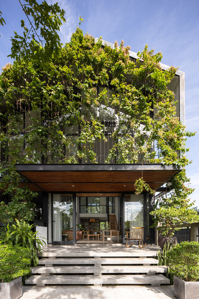 Mặt đứng với hệ thống dây leo xanh dọc theo mái nhà, hành lang và ban công giúp điều tiết ánh nắng trực tiếp chiếu vào đồng thời cho phép các vệt nắng chiếu vào khoảng trống một cách hiệu quả và mang lại sự riêng tư cho khu vực bên trong.