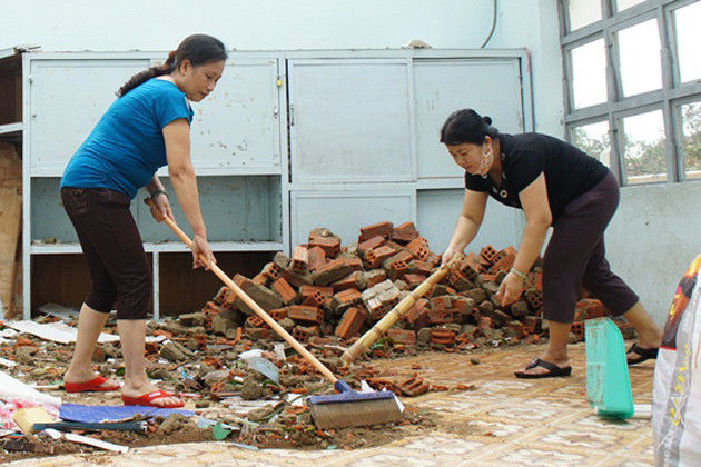 Cô giáo trường tiểu học Hoàng Văn Thụ, TP Đà Nẵng dọn dẹp hậu quả bão. Trong bão số 11 ngôi trường này bị tốc mái 5 phòng học, và một số phòng bị đổ tường. Ảnh: VGP/Minh Trang