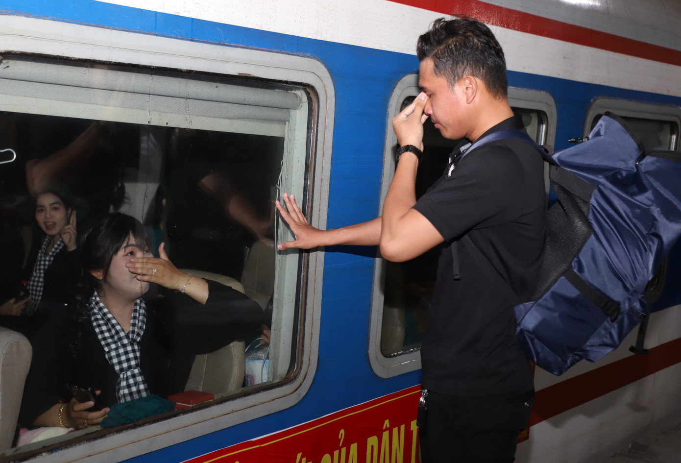 Đôi bạn trẻ bịn rịn, xúc động chào nhau tại sân ga.