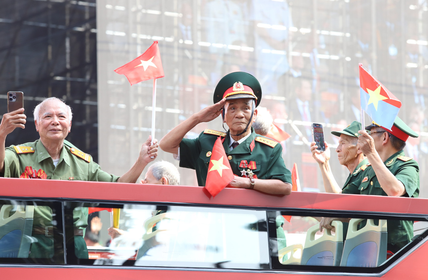 Người cựu chiến binh già lặng chào đại biểu khi chiếc xe buýt hai tầng đưa ông cùng đồng đội tiến qua lễ đài của lễ kỷ niệm.