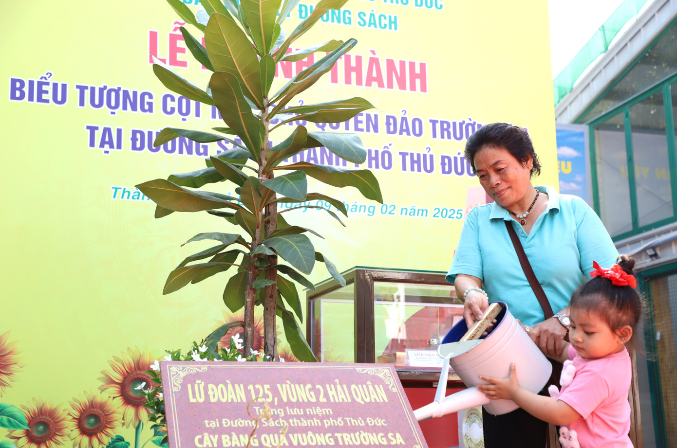 Hai bà cháu tưới nước cho cây bàng vuông vừa được trồng.