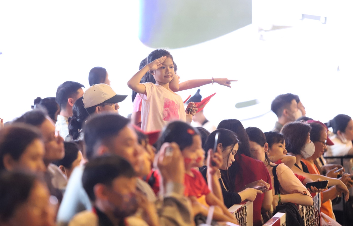 Một em bé đưa tay chào khi đoàn diễu binh, diễu hành đi qua khu vực lễ đài trên đường Lê Duẩn.