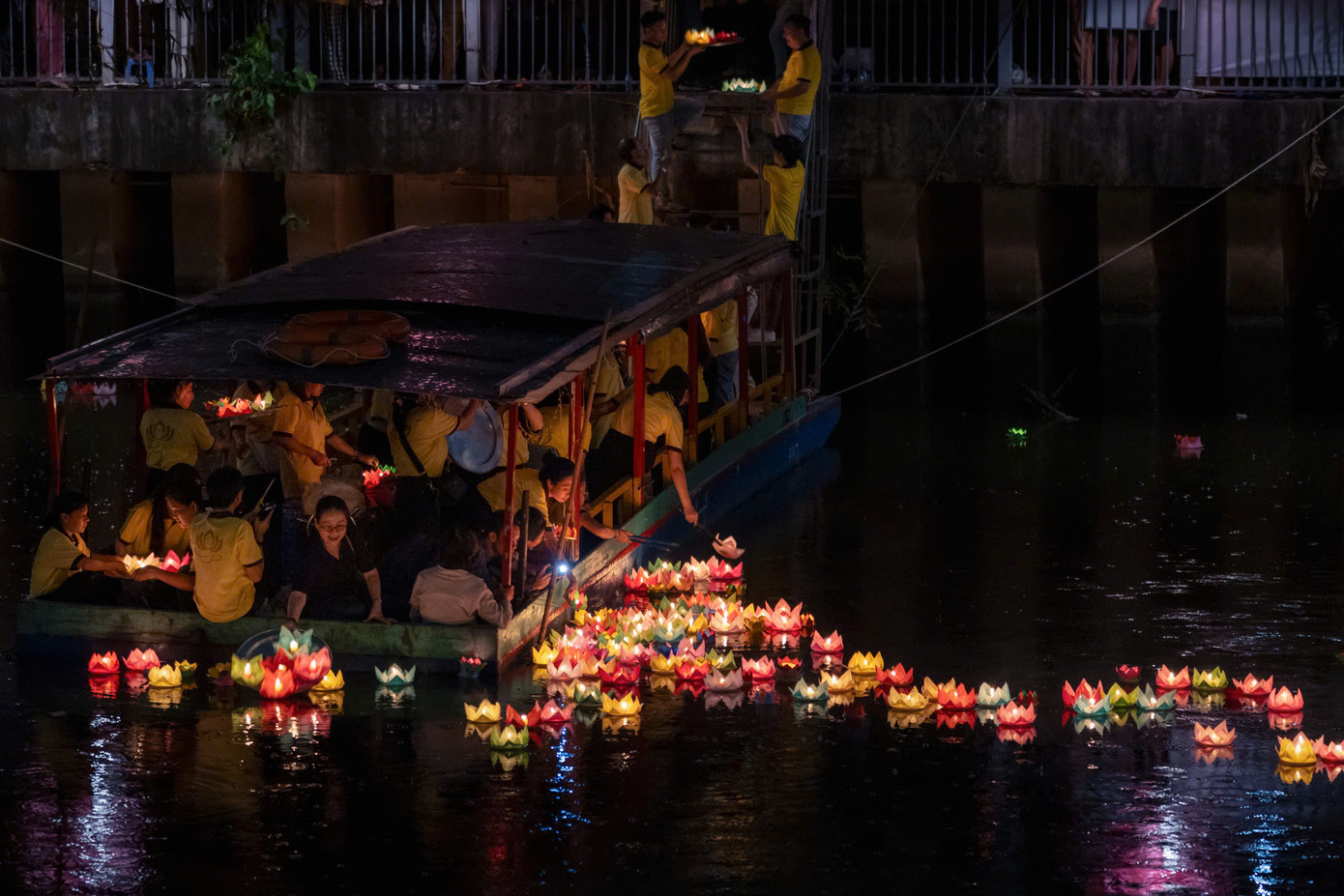 Các tình nguyện viên di chuyển hoa đăng từ bên trong chùa đến bờ kênh rồi thả trôi theo dòng nước.